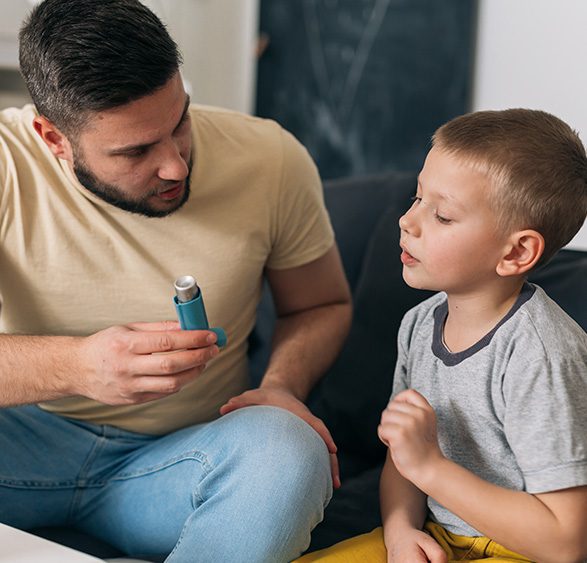 father explaining to his son how to use asthma pump